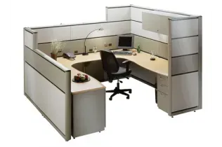 A cubicle with a desk and chair and a computer on it.