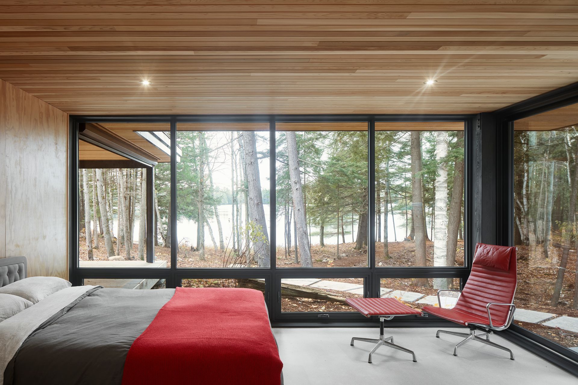 A bedroom with a large bed , chair , and lots of windows.