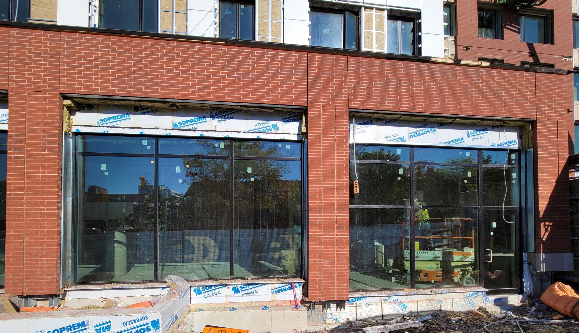 Building exterior under construction with brick facade and large glass windows.
