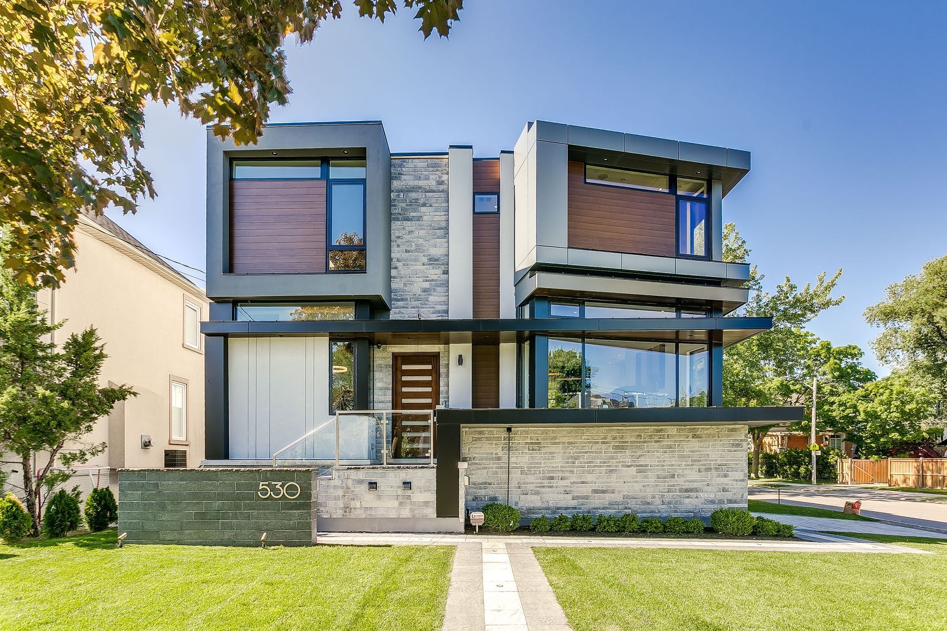A modern house with a lot of windows is sitting on top of a lush green lawn.