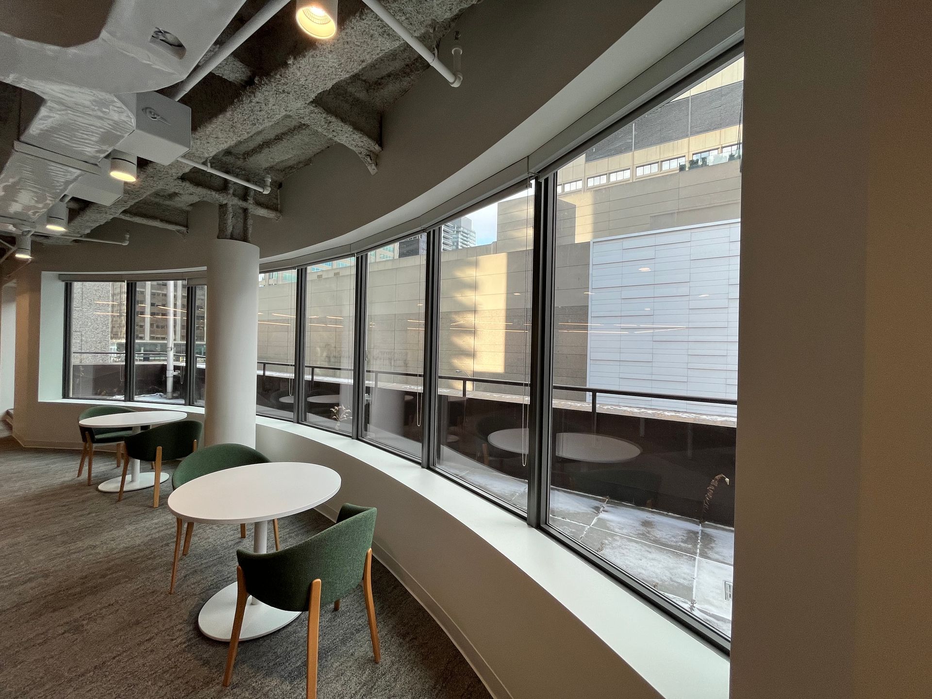 A room with tables and chairs in front of a large window.