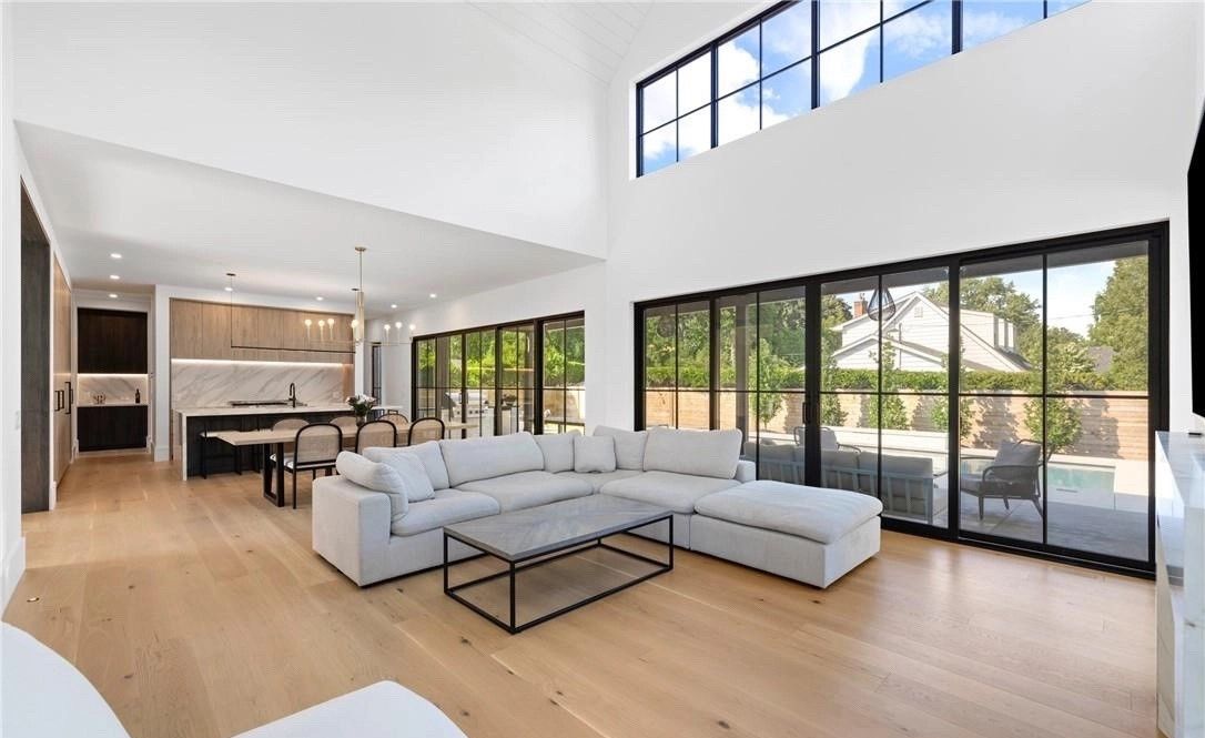 A living room with a couch , coffee table , and lots of windows.