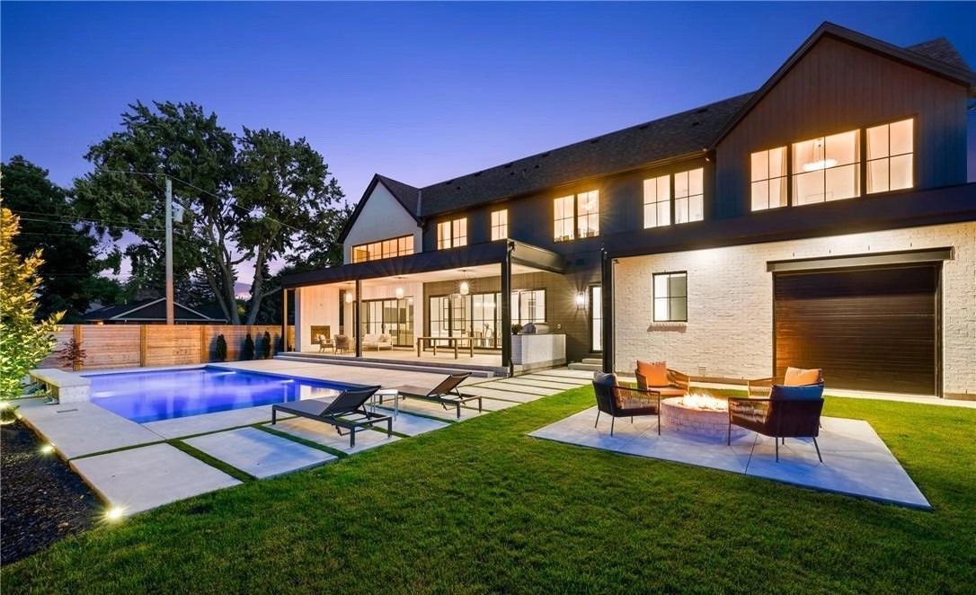 A large house with a swimming pool in the backyard at night.