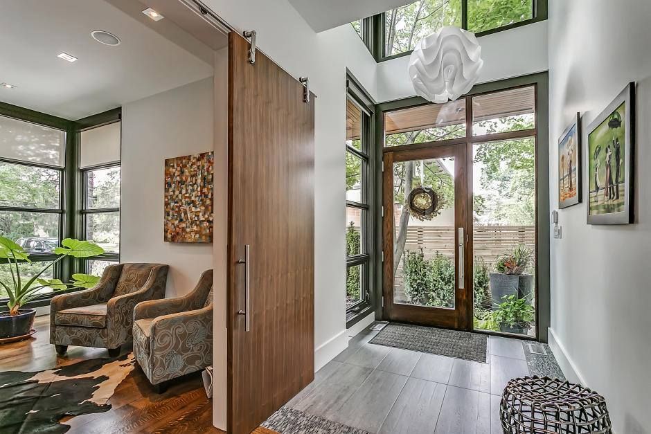 A hallway in a house with a sliding barn door leading to the front door.