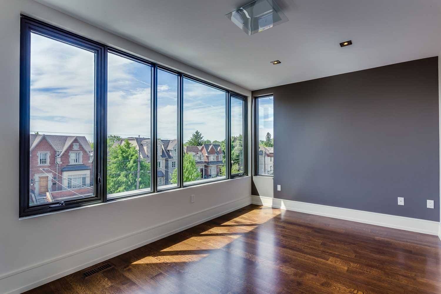 An empty room with a lot of windows and hardwood floors.