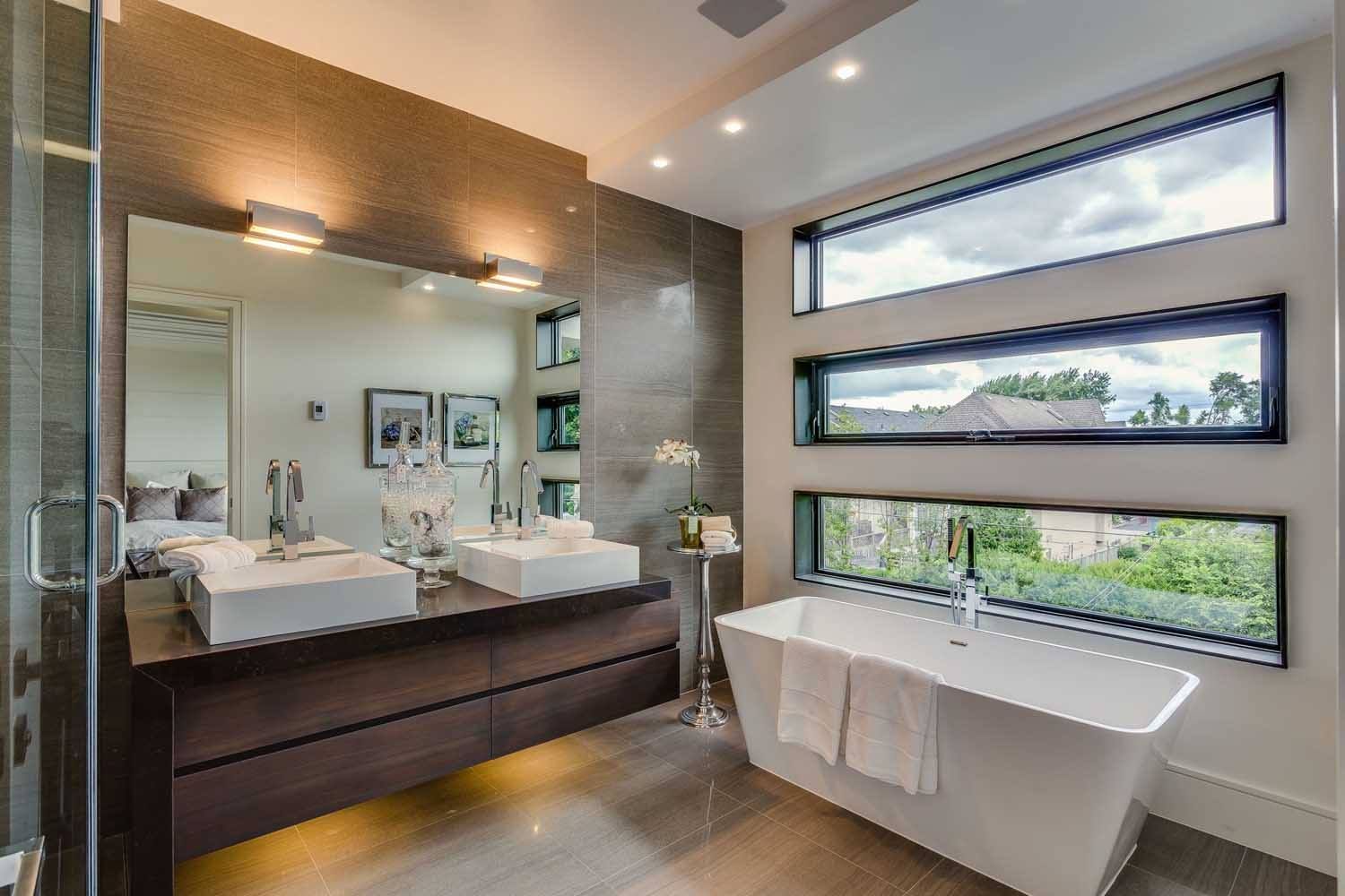 A bathroom with two sinks , a tub and a large mirror.