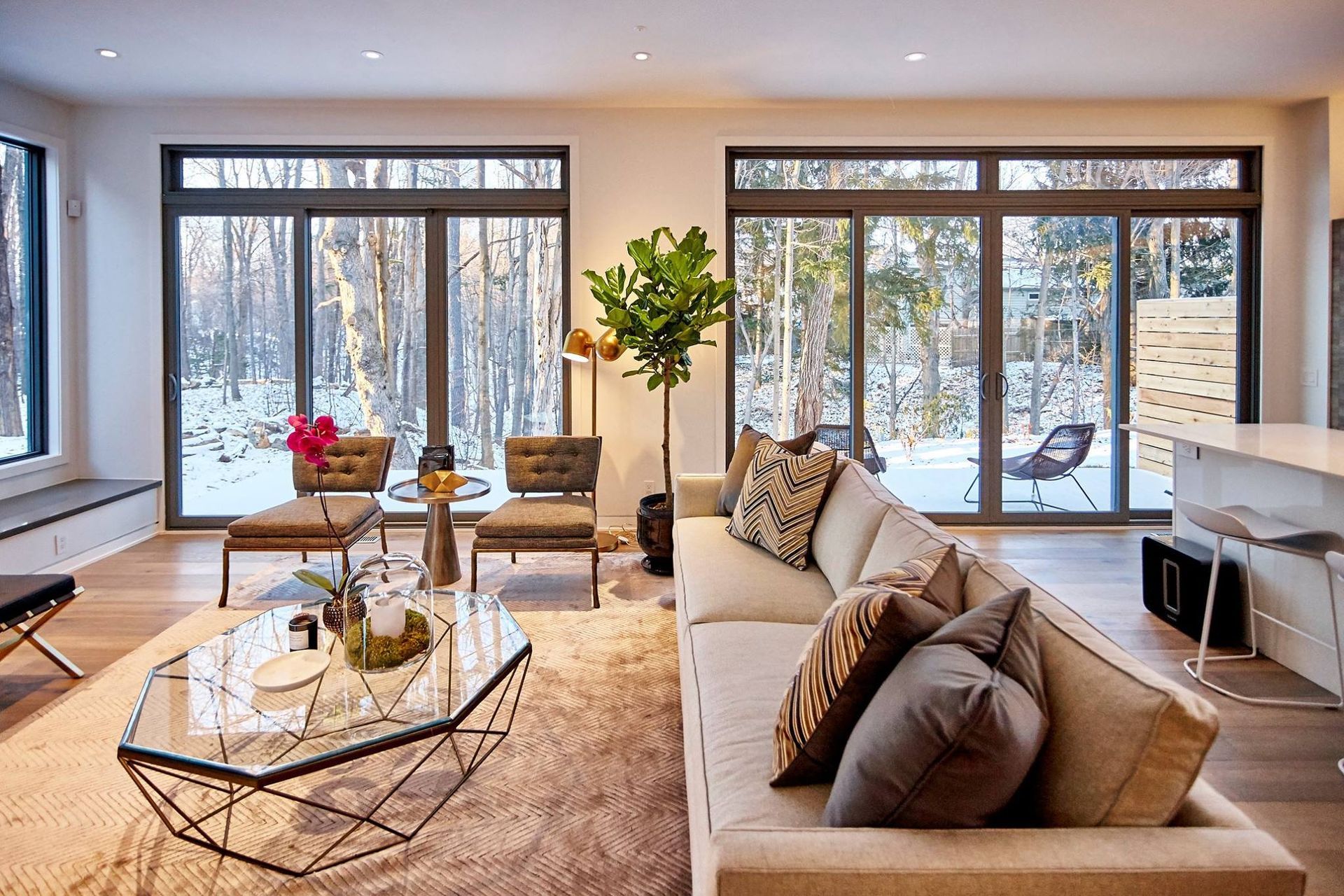 A living room with a couch , chairs , a coffee table and a lot of windows.