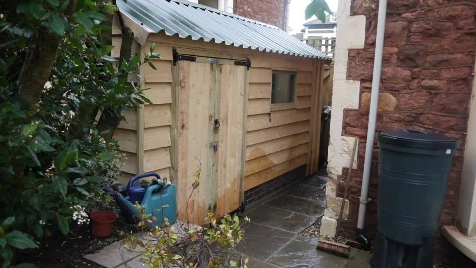 Urban Paving Bristol | A wooden shed with a blue watering can in front of a brick building.