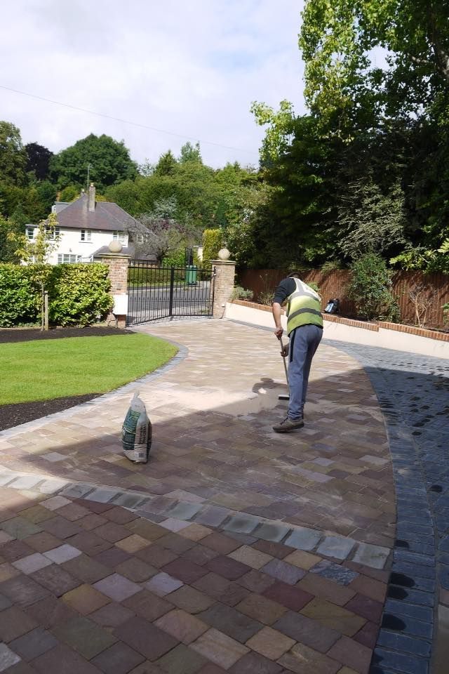 Urban Paving Bristol | A man is working on a brick driveway in a backyard.