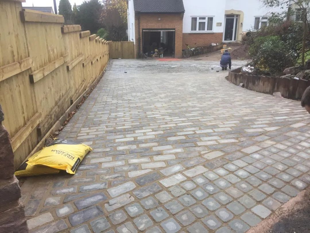 Urban Paving Bristol | A brick driveway leading to a house with a wooden fence.