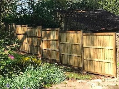 Urban Paving Bristol | A wooden fence is surrounded by trees and flowers in a garden.