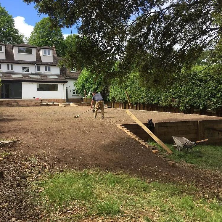 Urban Paving Bristol | A man is raking dirt in front of a house