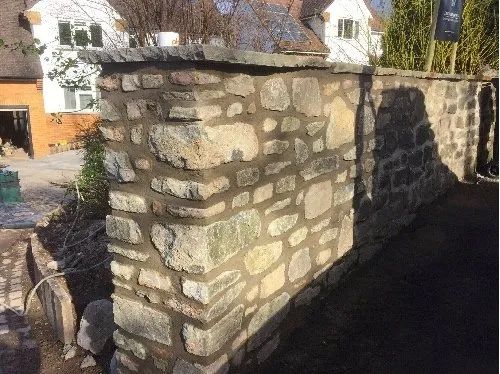 Urban Paving Bristol | A stone wall is being built in front of a house.