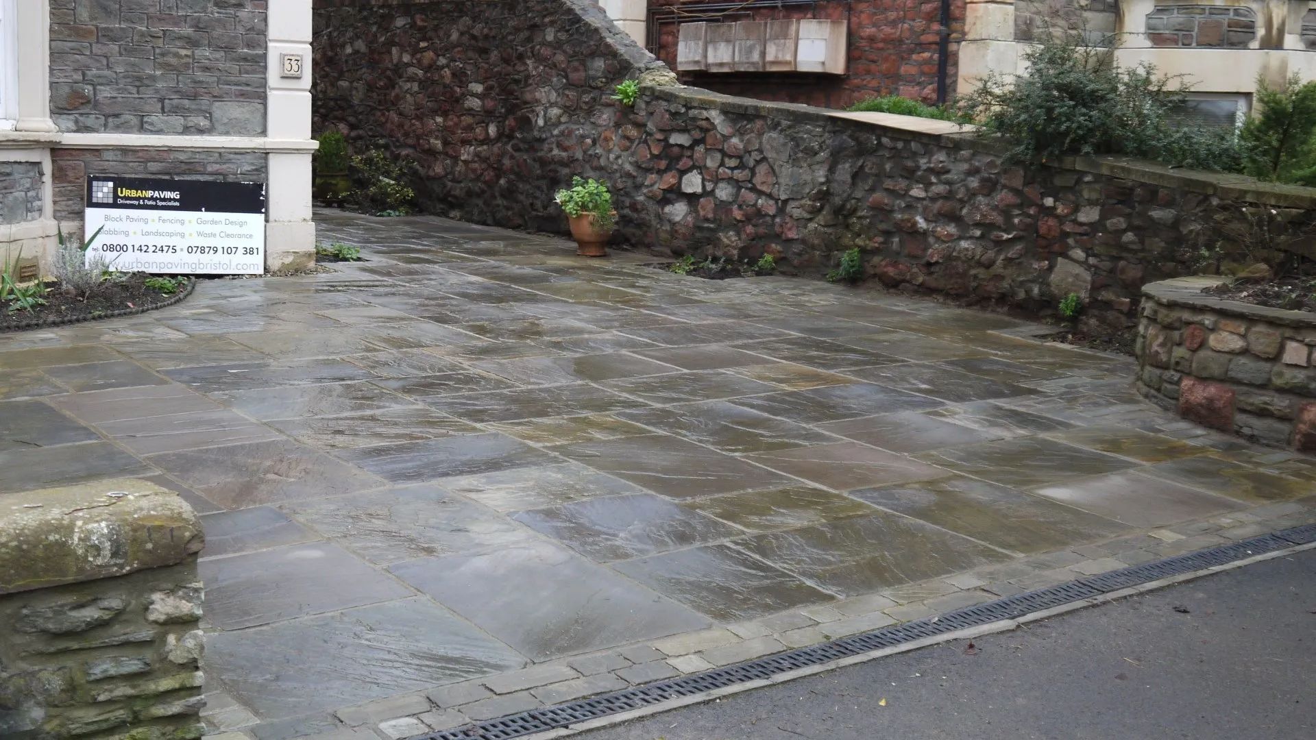 Urban Paving Bristol | A stone driveway with a stone wall in the background.
