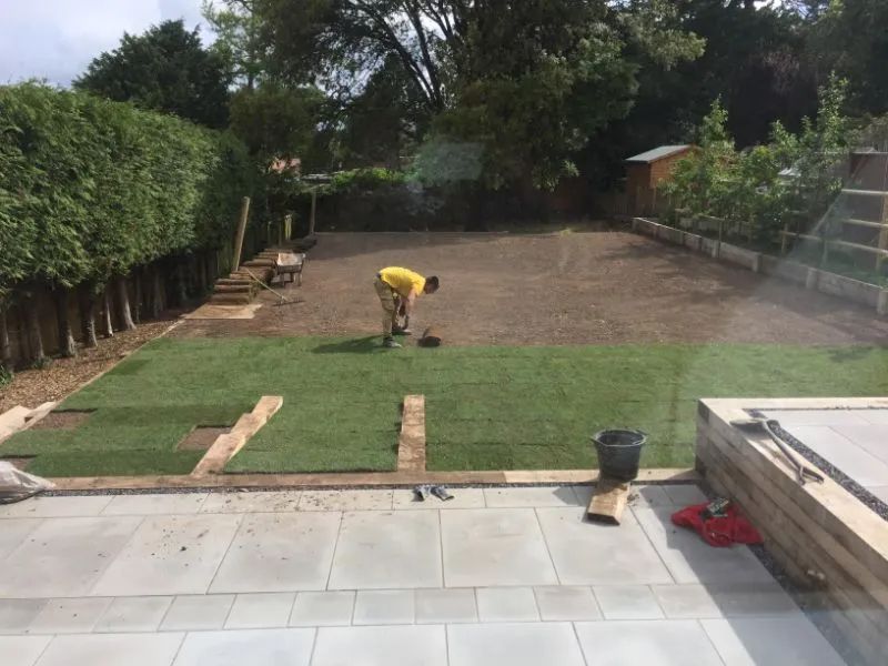 Urban Paving Bristol | A man in a yellow shirt is working on a lawn in a back garden.
