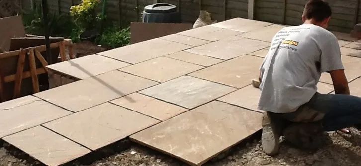 Urban Paving Bristol | A man is laying a patio in a garden.