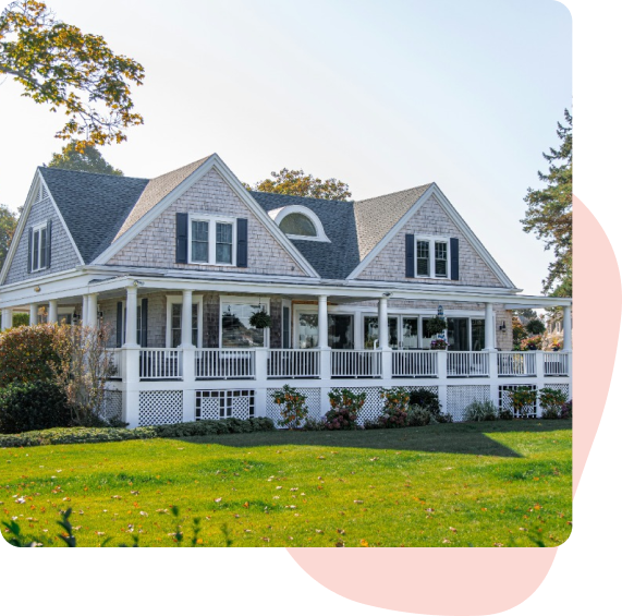 a large white house with a large porch is sitting on top of a lush green field .