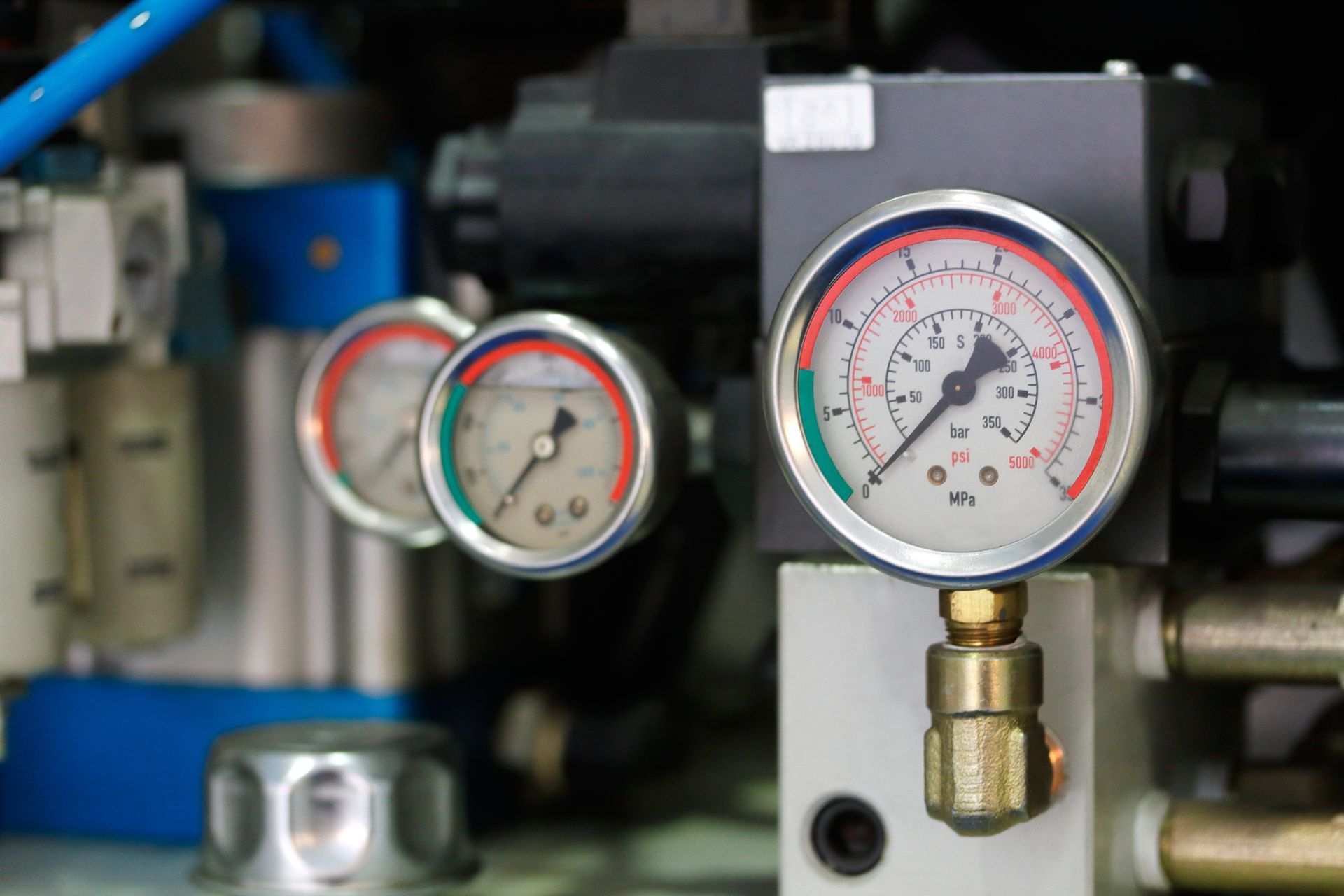 Close-up of industrial machinery with three pressure gauges, indicating pressure levels.