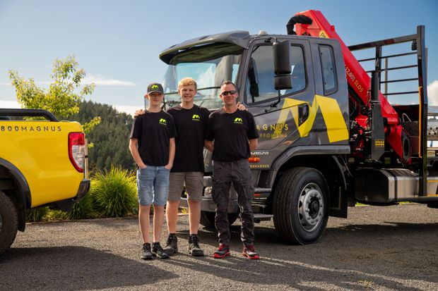 Three men are posing for a picture in front of a truck.