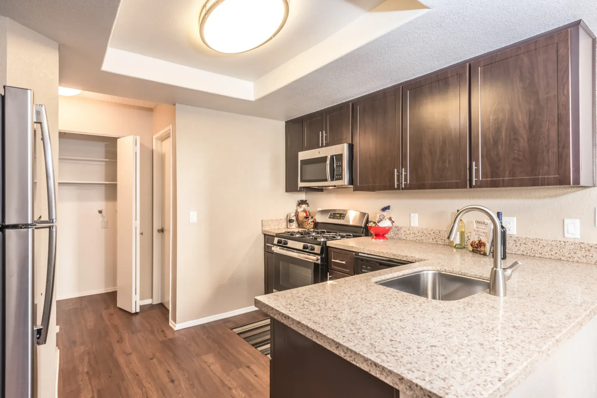 Kitchen in an apartment with dark wood cabinets and granite countertops.