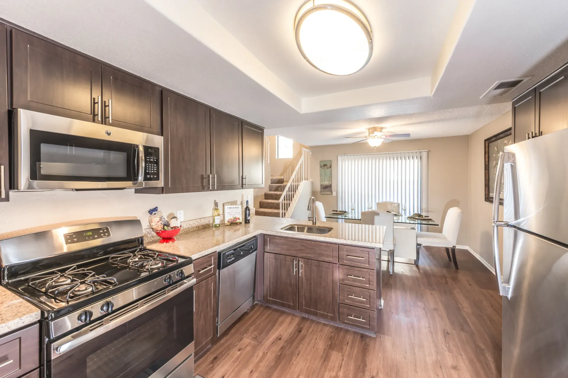 Modern apartment kitchen with stainless steel appliances and dark wood cabinets.