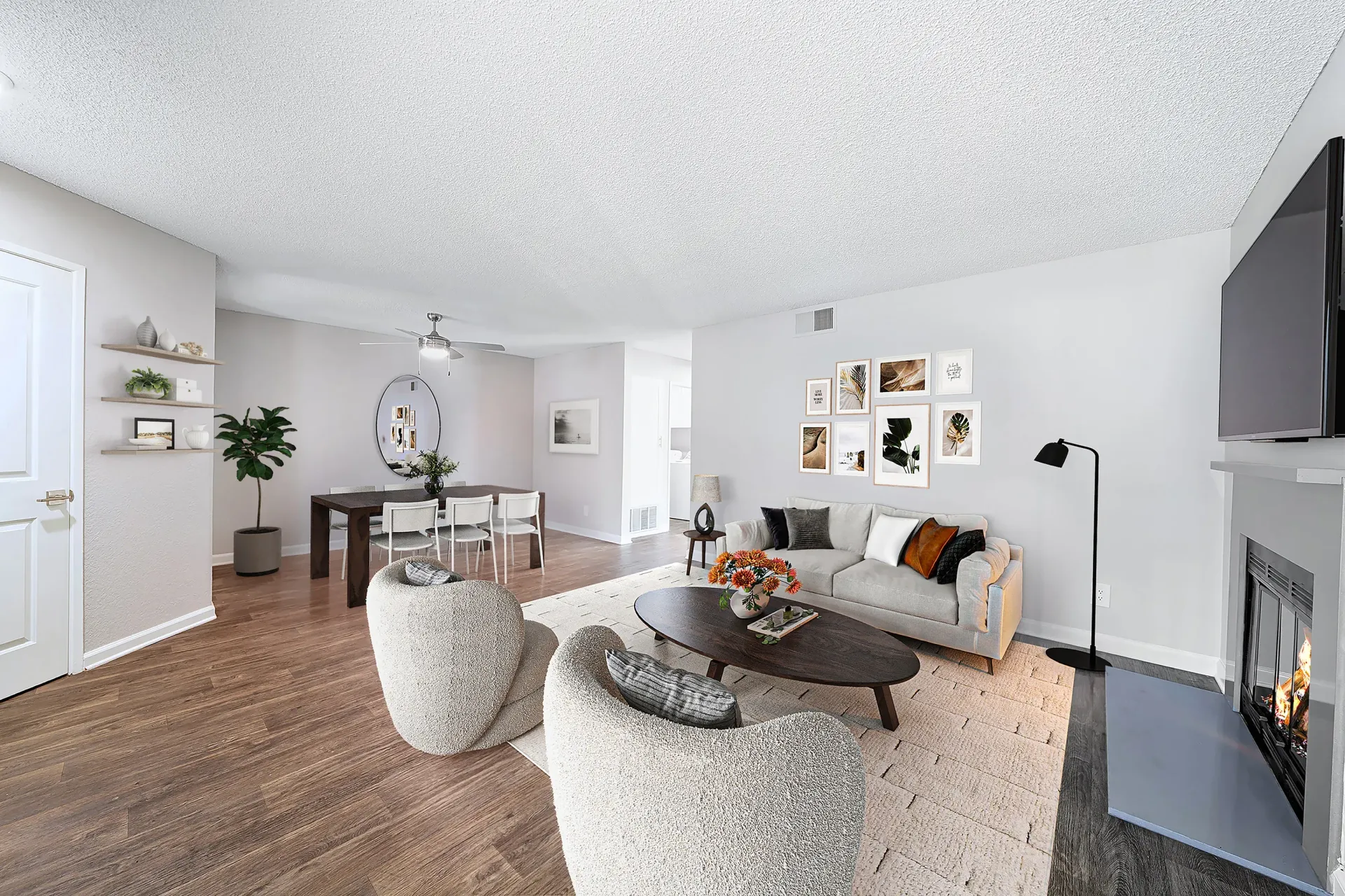 Open-concept living room in a modern apartment with sofa, lounge chairs, fireplace, and dining area.