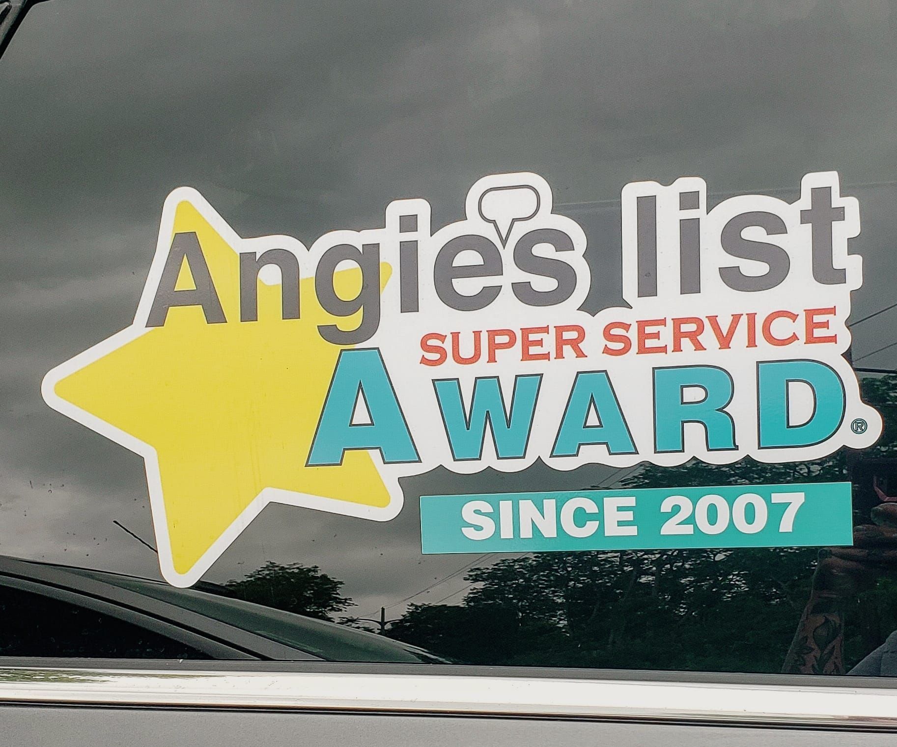 Angie's List Super Service Award sticker on a car window, since 2007. Yellow star, blue and red text.