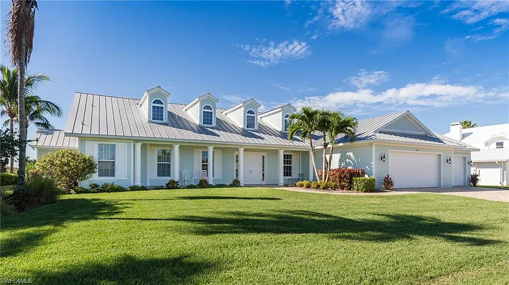 Light blue house with green lawn and blue sky.