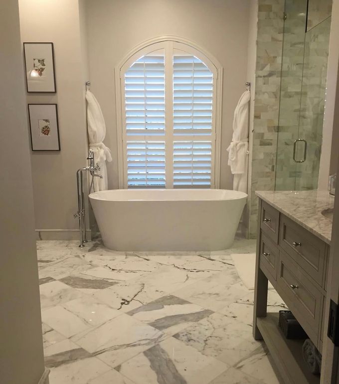 A bathroom with a tub , sink , mirror and shower.