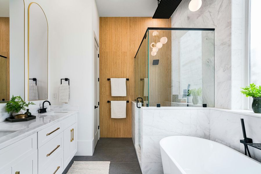 A bathroom with a tub , sink , mirror and shower.