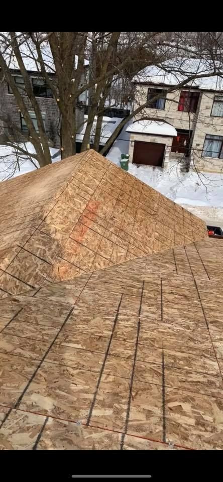 Un toit est en train d'être construit dans la neige avec une maison en arrière-plan.