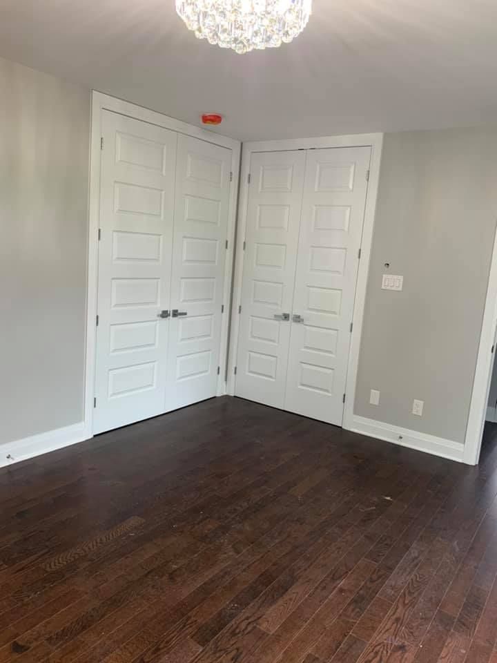 Une pièce vide avec du parquet et des portes blanches.