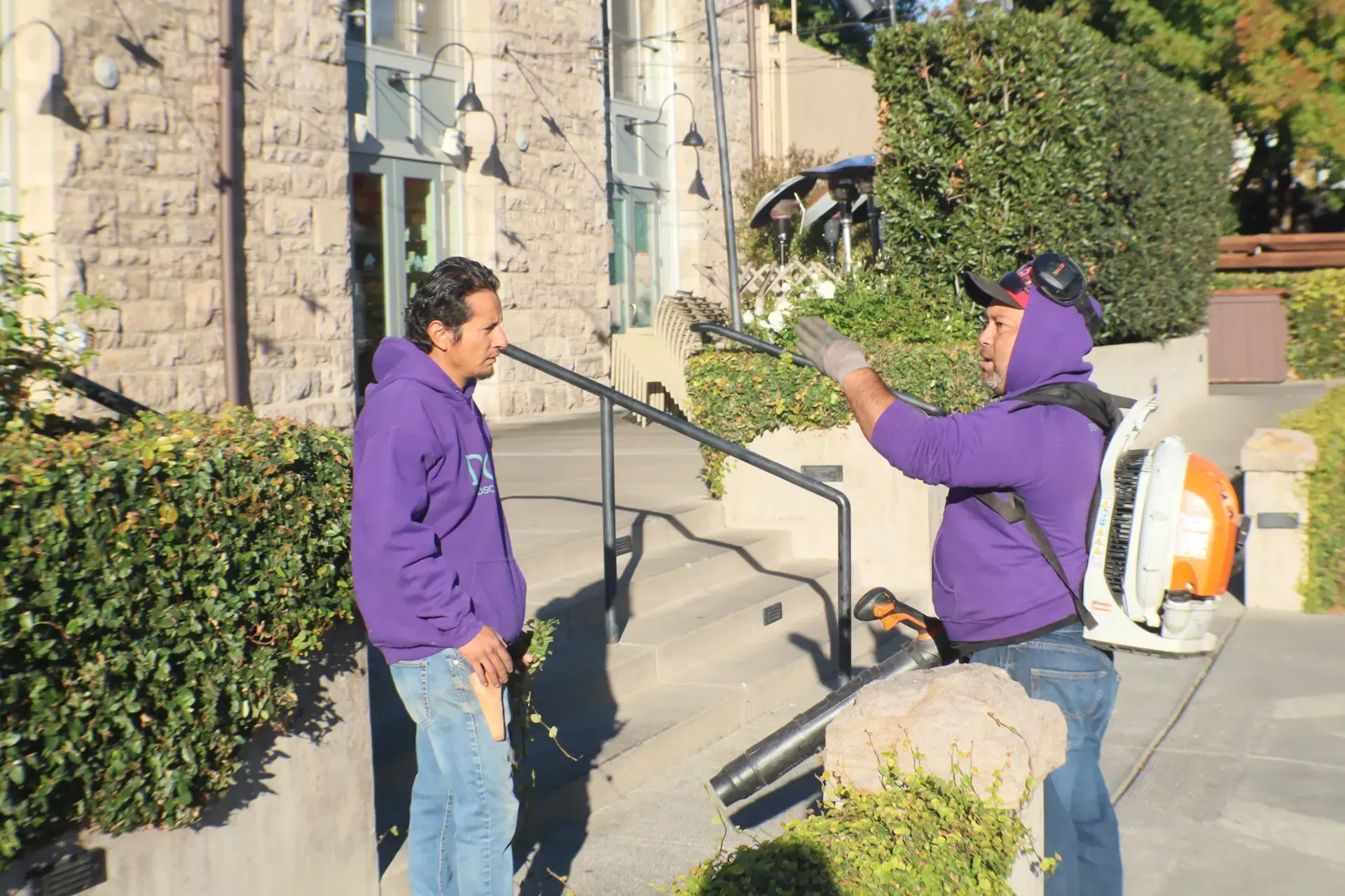 A man in a purple hoodie is talking to another man