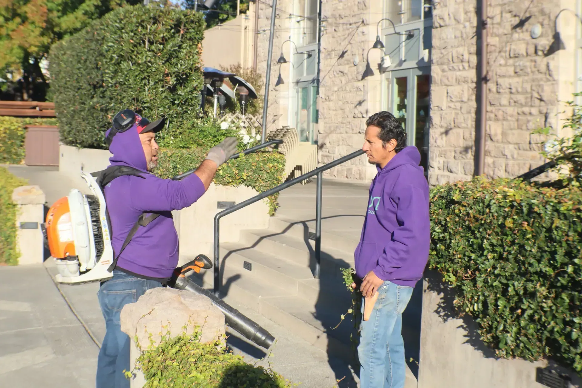 A man in a purple hoodie is talking to another man