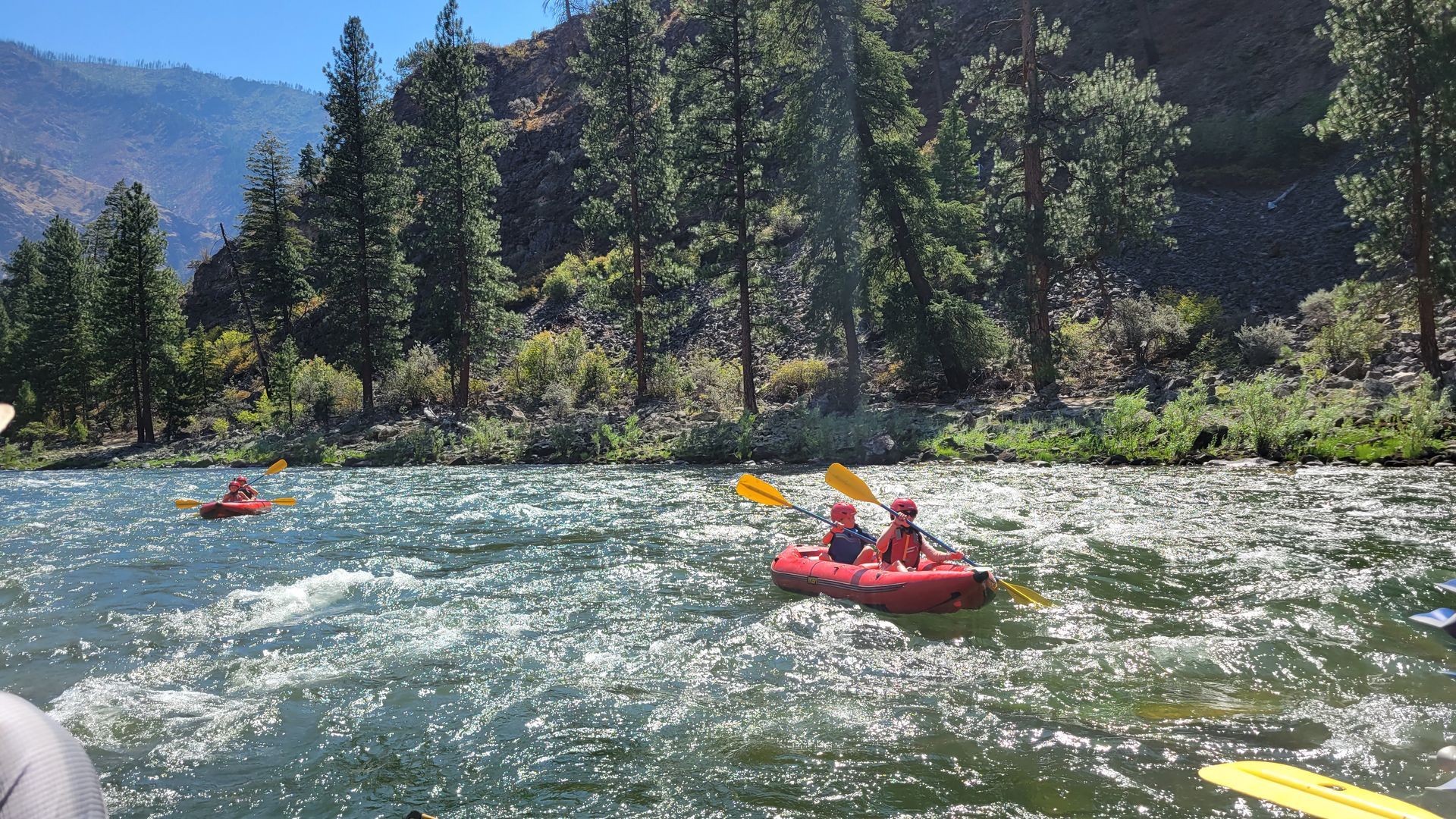 A couple of people are kayaking down a river.