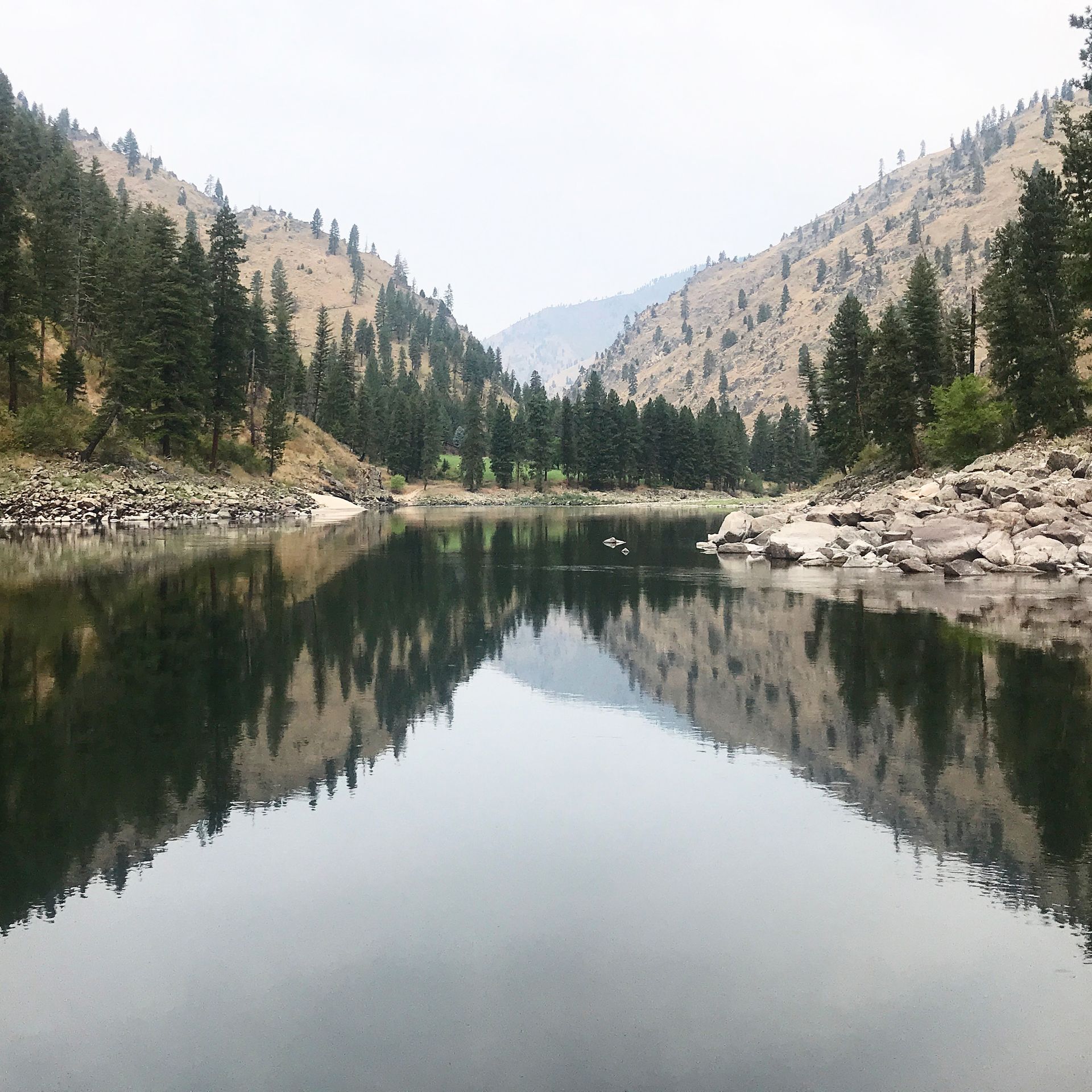 A lake with mountains in the background and trees reflected in the water