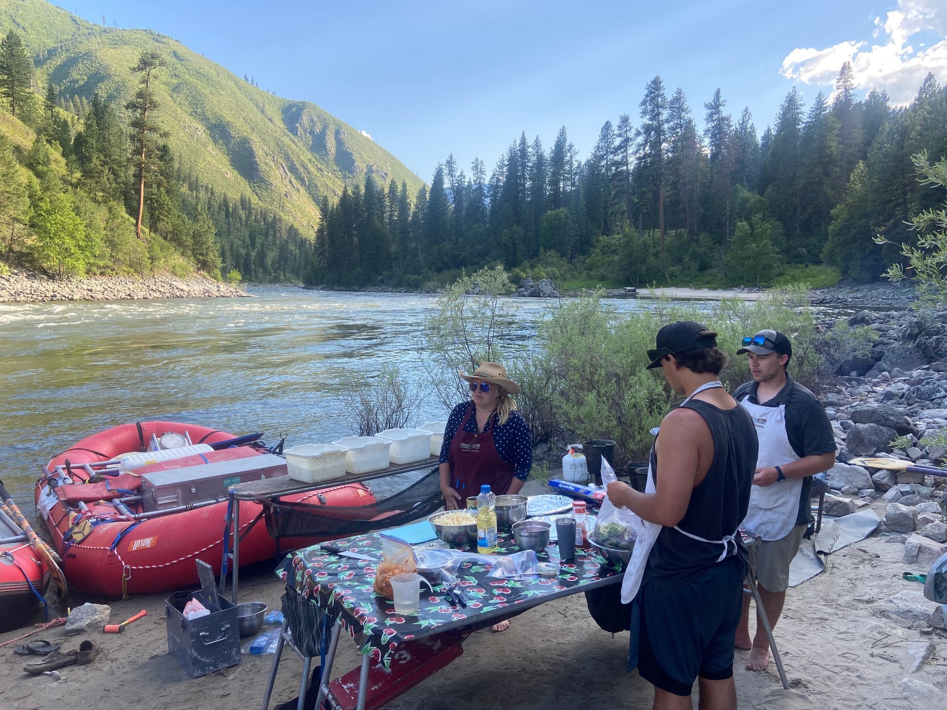 A group of people are standing around a table next to a river.