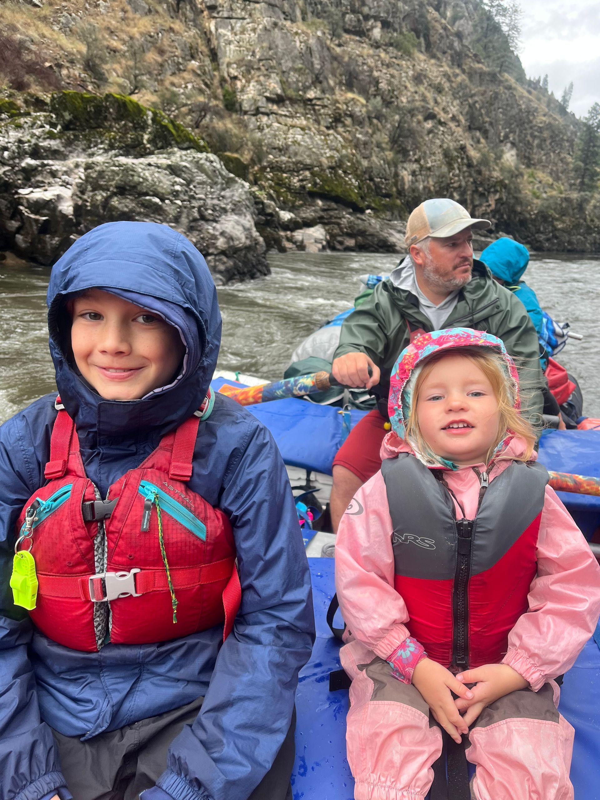 A man and two children are sitting on a raft in the water.