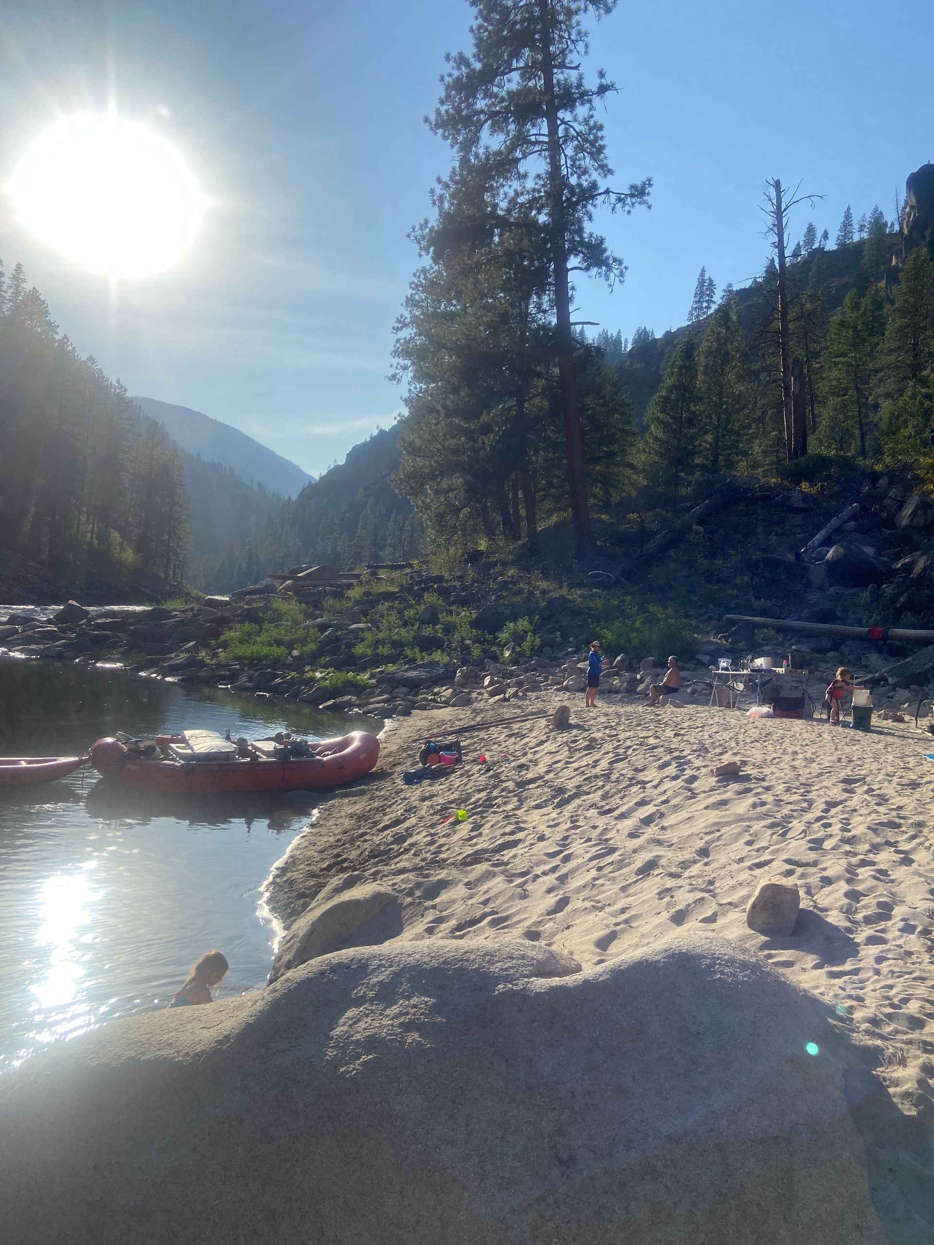 A sandy beach with a river and mountains in the background