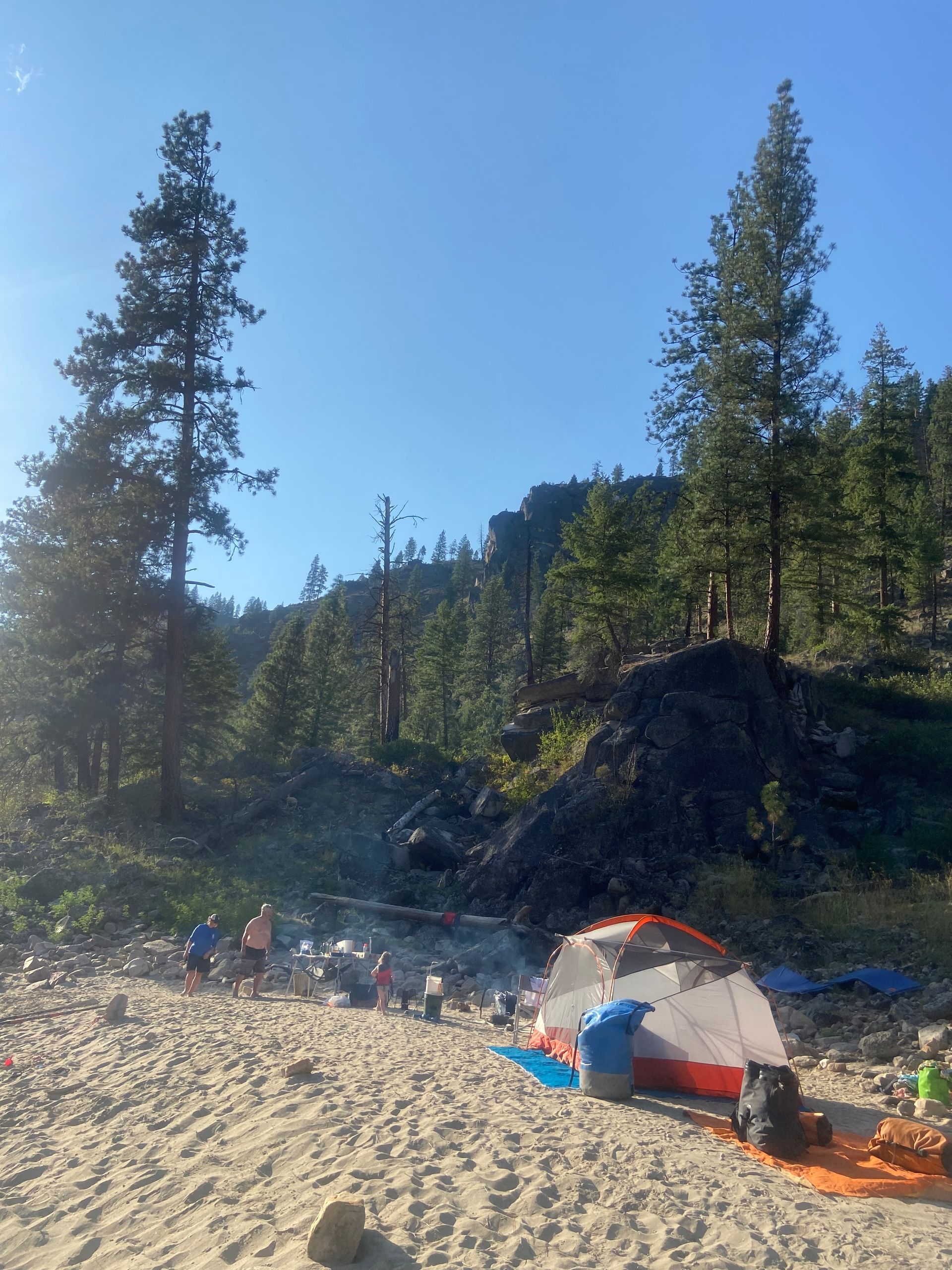 A group of people are camping on a sandy beach.