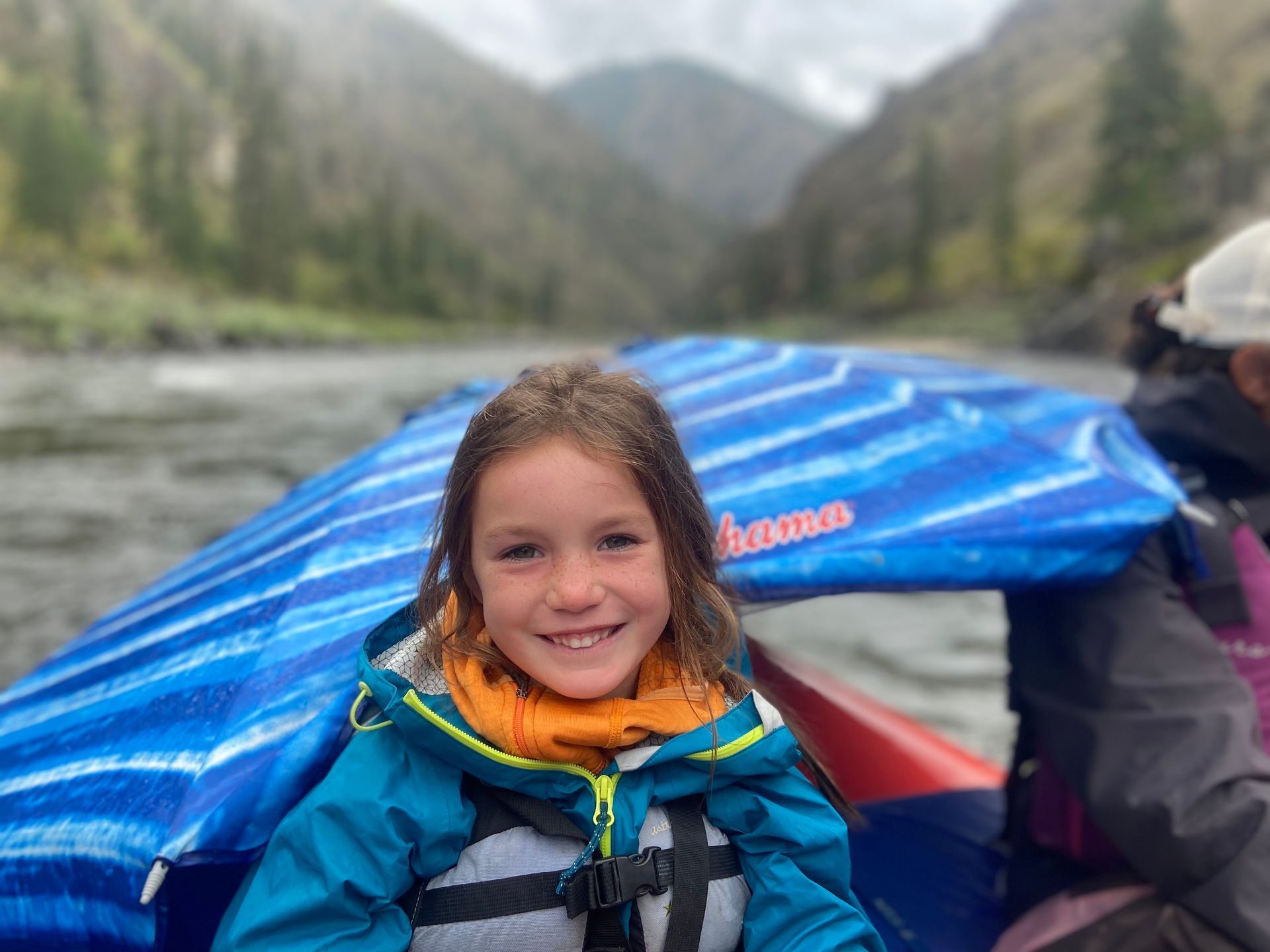 A little girl is sitting in a boat on a river.