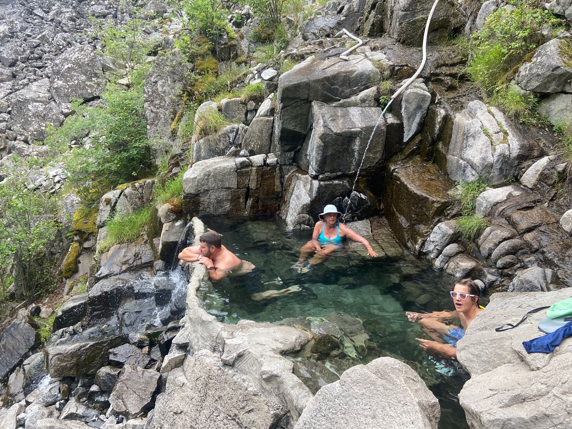 A group of people are sitting in a hot spring surrounded by rocks.