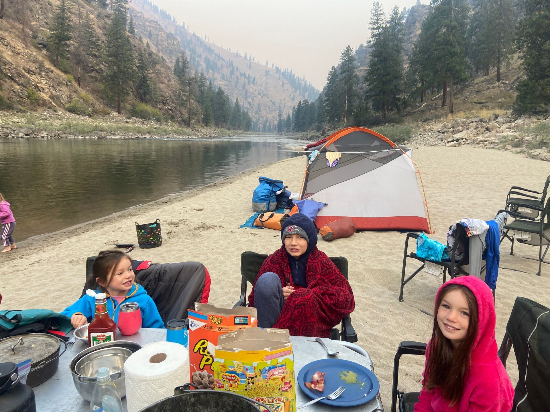 A group of children are sitting at a table in front of a tent.