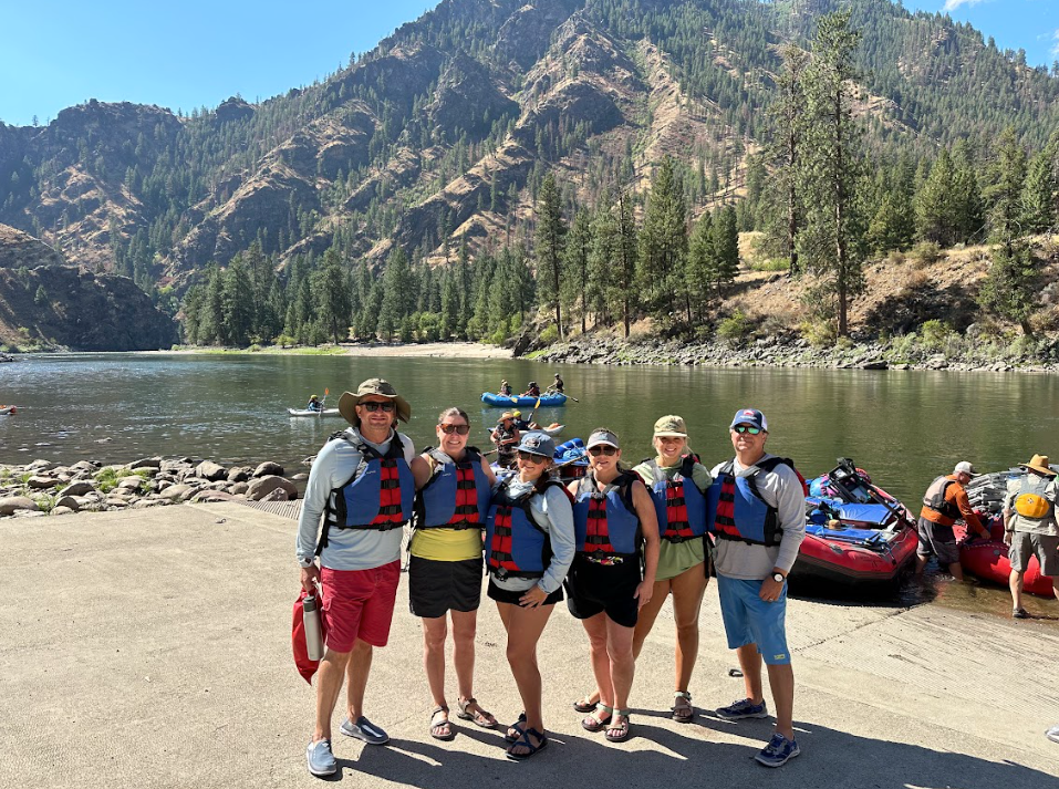 A group of people are posing for a picture in front of a lake.