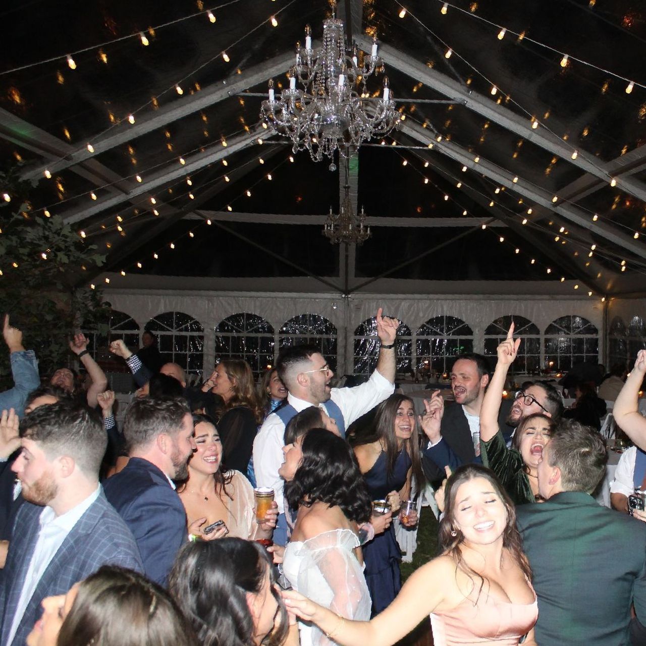 A large group of people are dancing under a clear roof