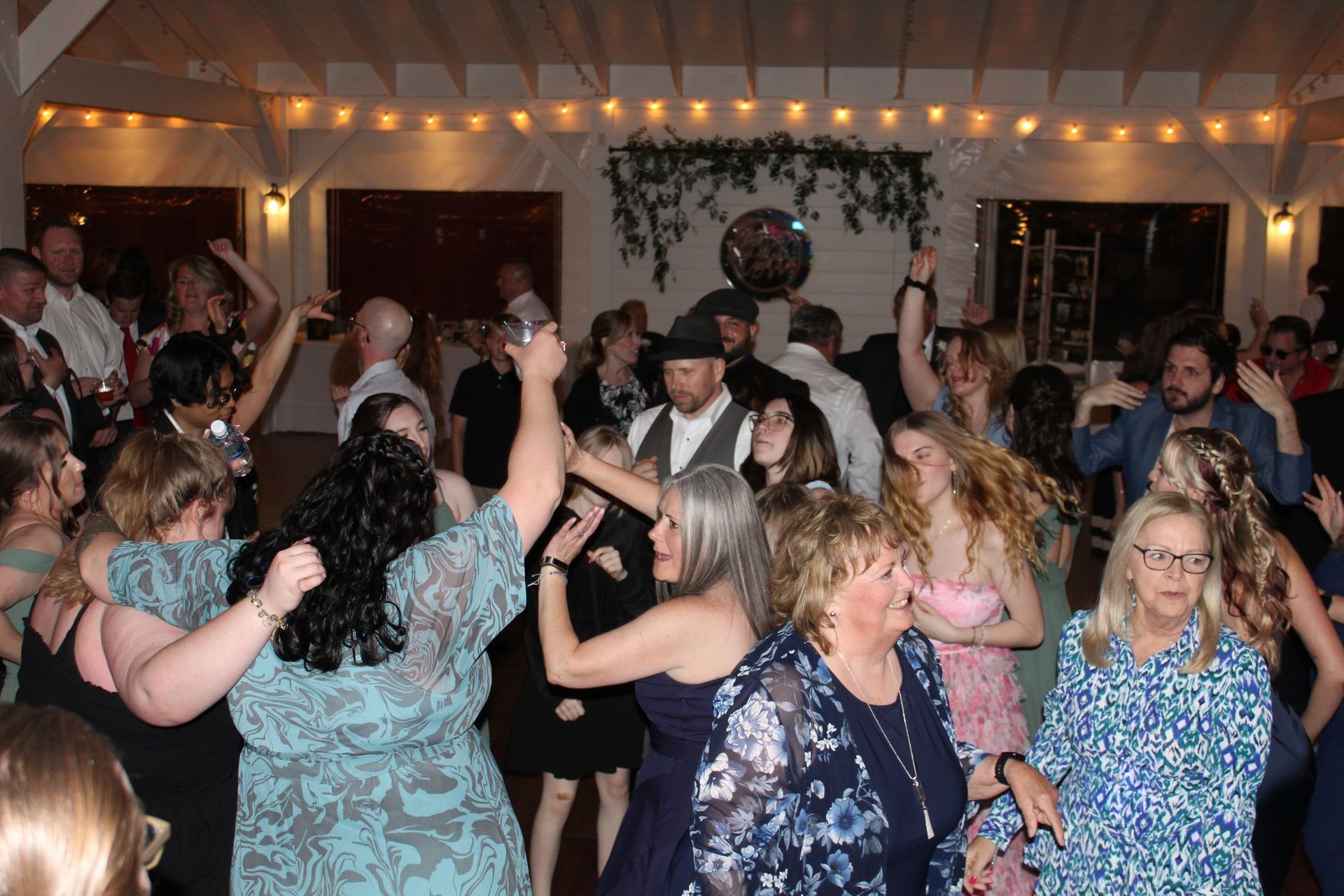 People dancing at a party in a decorated room with string lights.