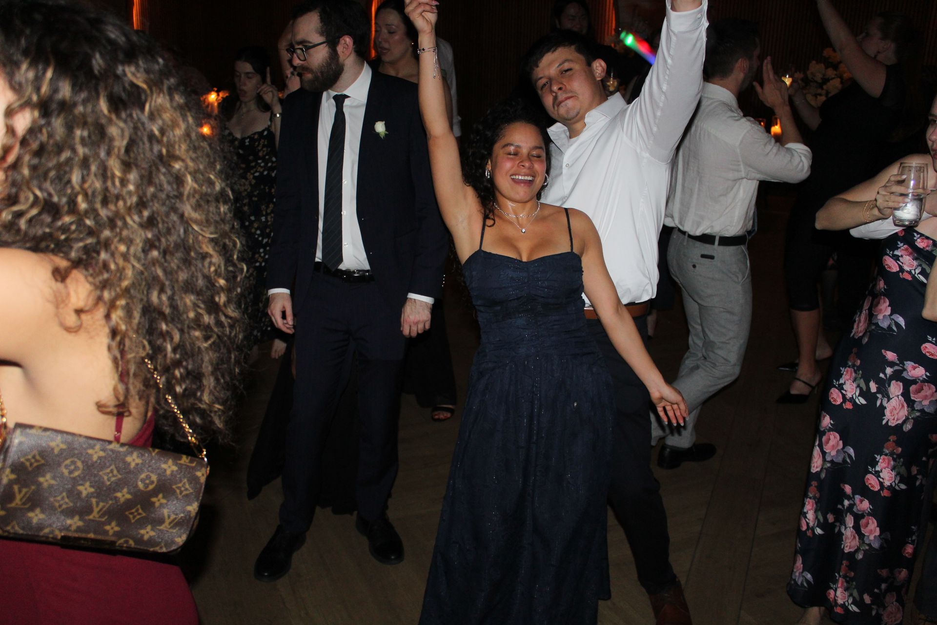 People dancing at an event. A woman in a blue gown raises her arm as a man dances beside her.