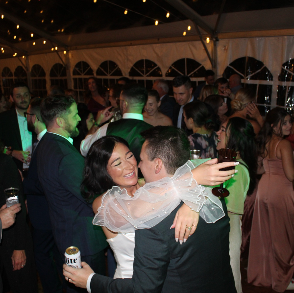 A man holding a can of miller lite is hugging a woman