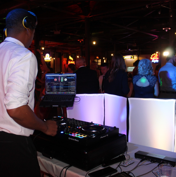 A man wearing headphones is playing music at a party