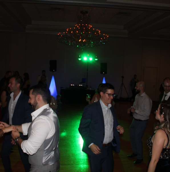 A group of people are dancing in a dark room with green lights